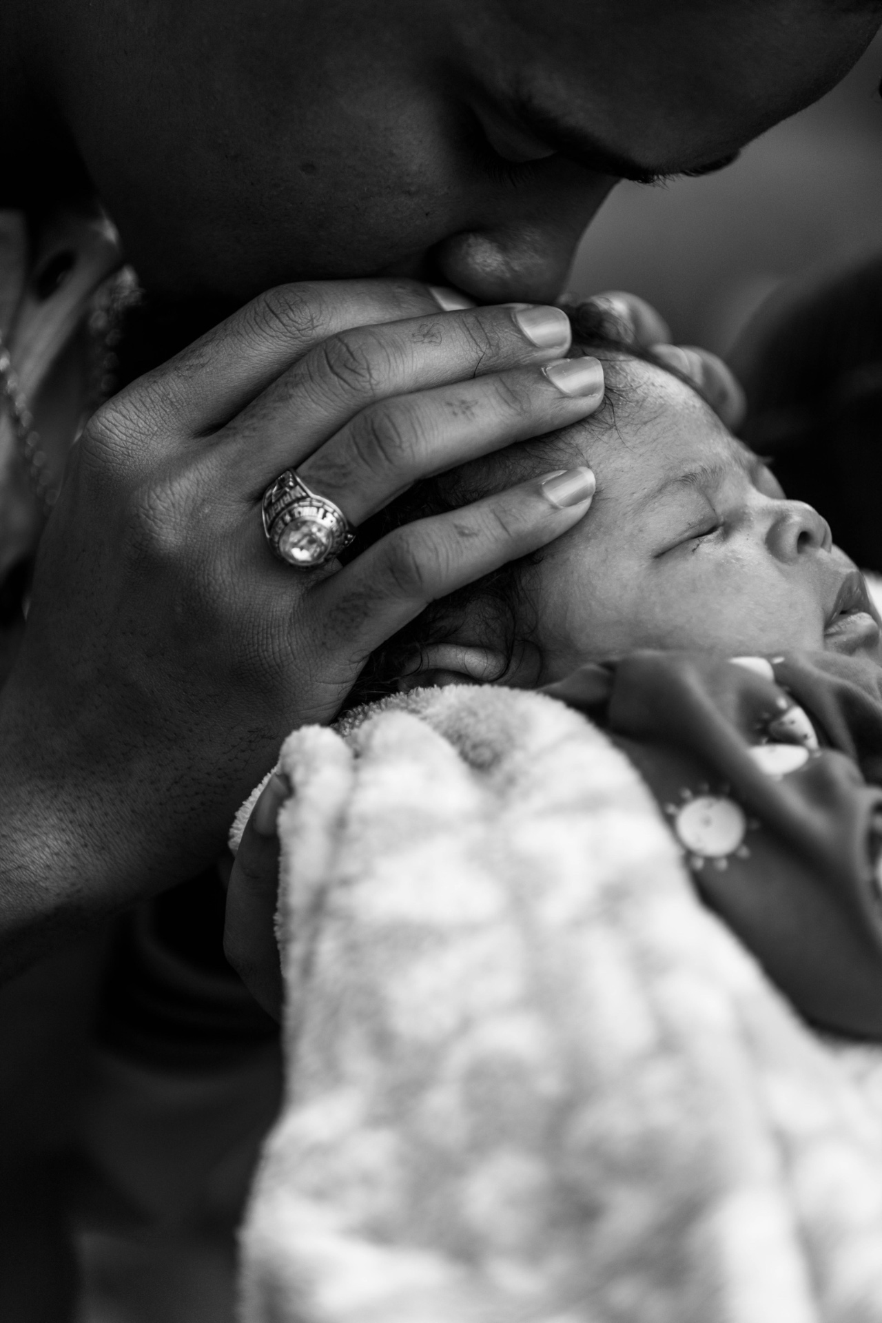 Black-and-white portrait of Andrick Wright kissing the head of his sleeping newborn baby