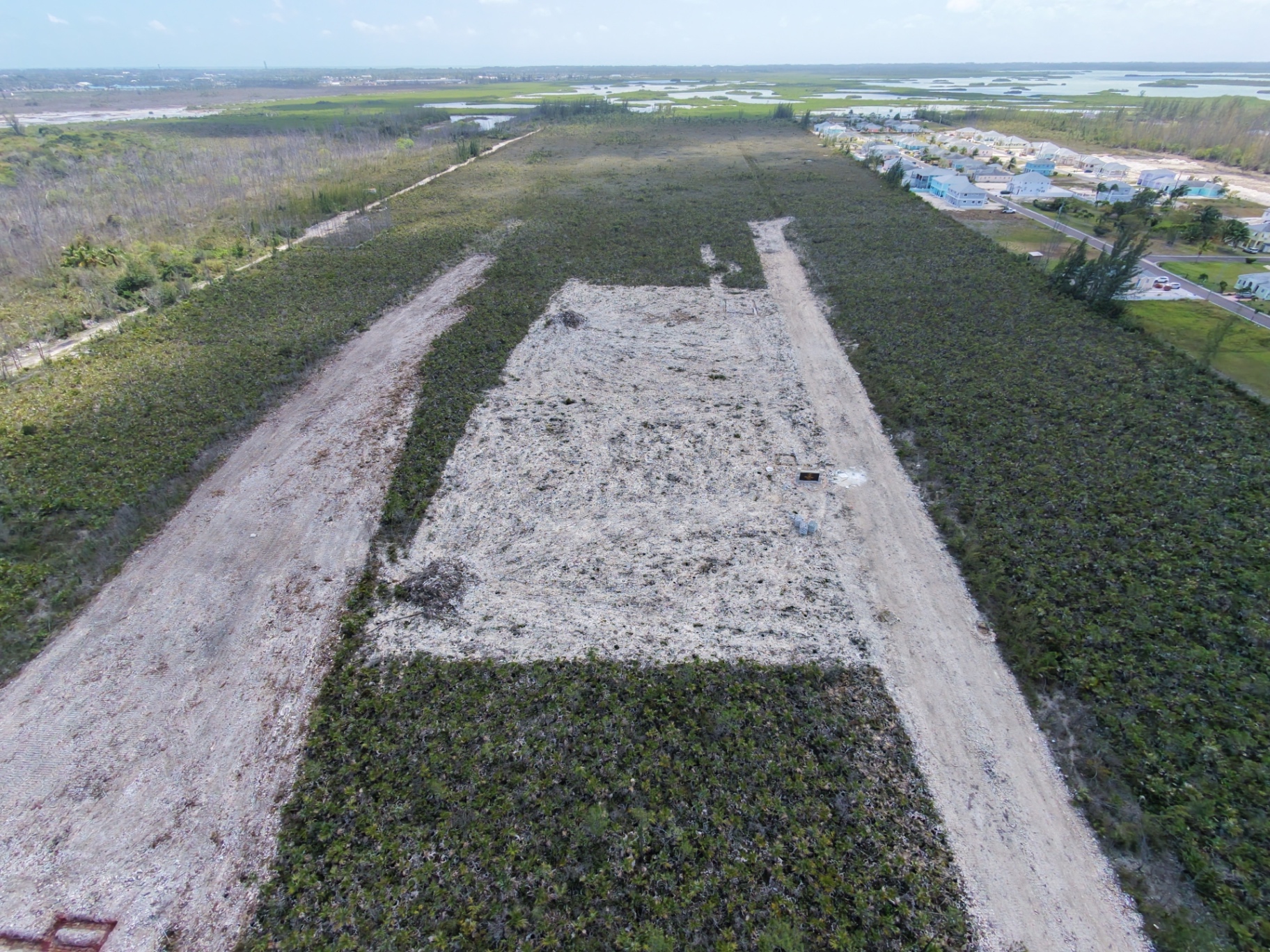 Aerial photograph of a cleared residential lot beside coastal wetlands and new homes