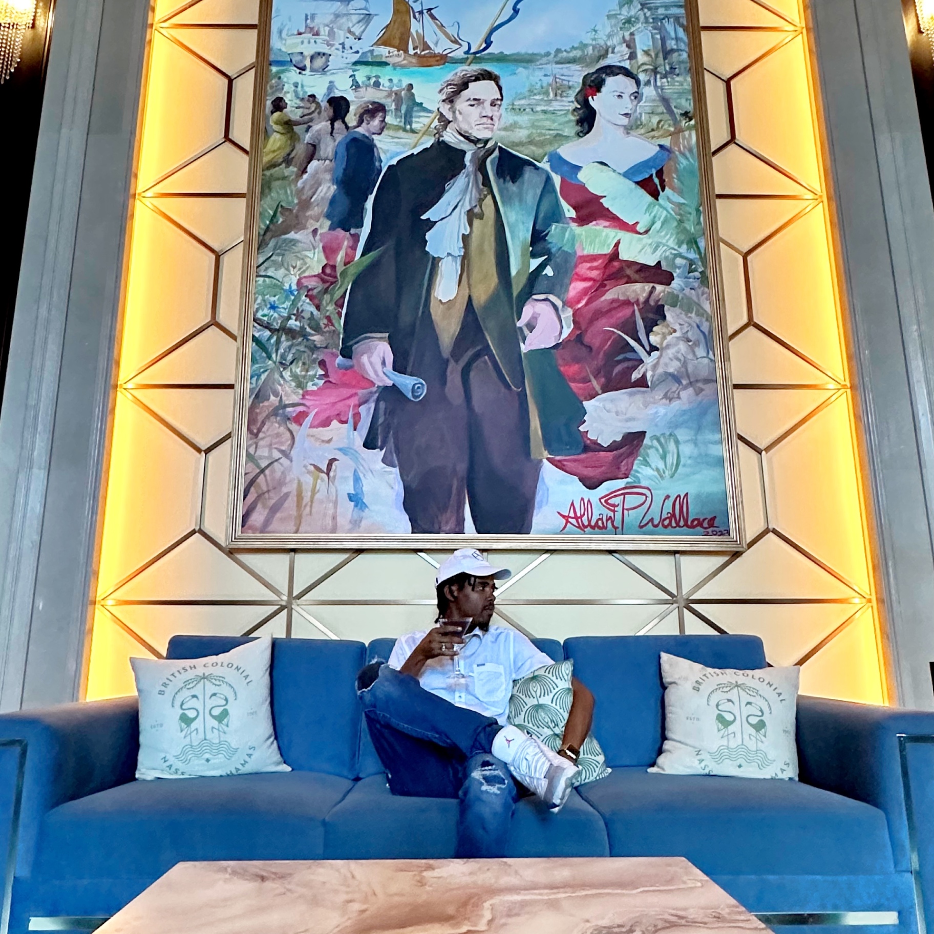 Andrick Wright seated on a blue sofa beneath a large painting at the British Colonial hotel in Nassau