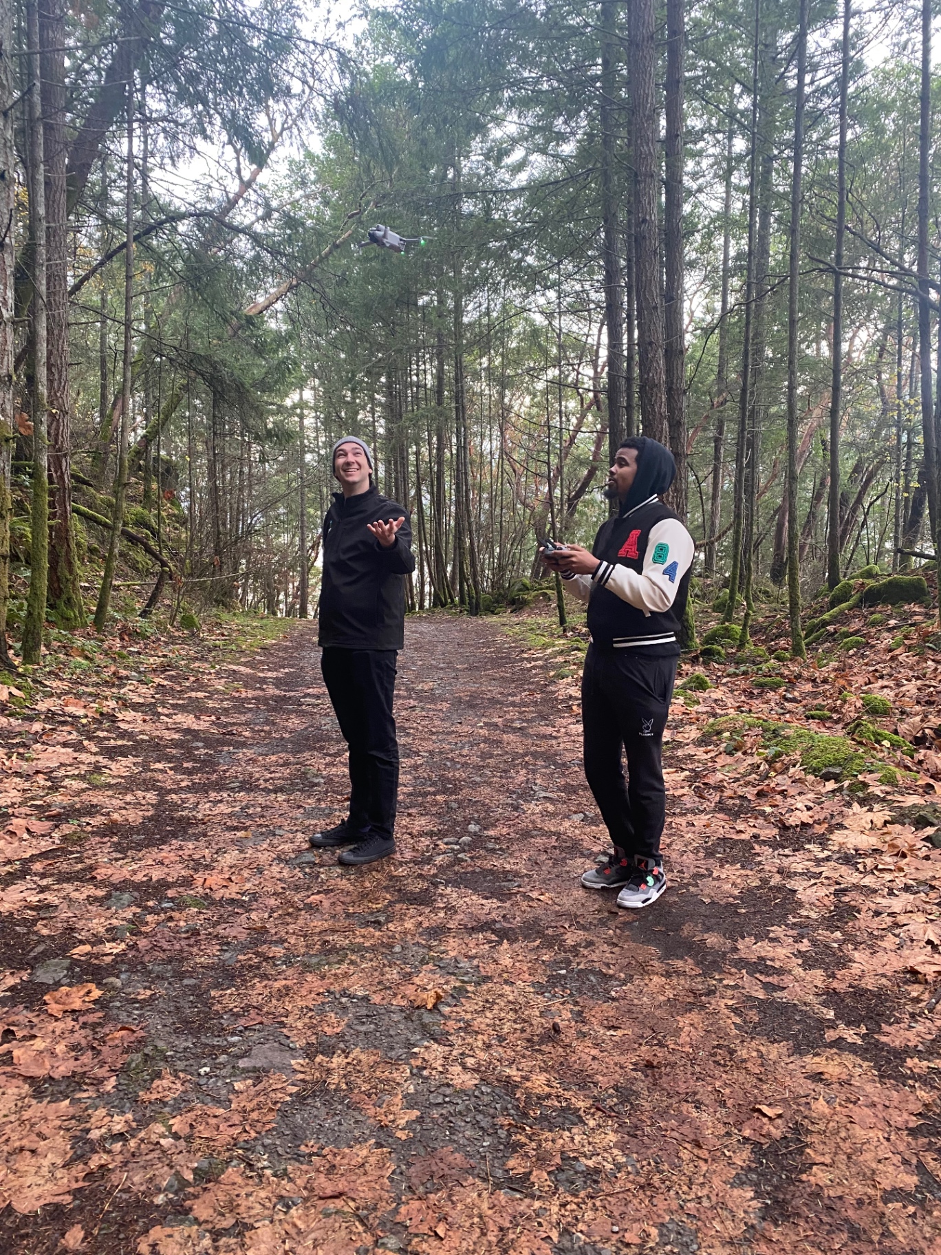 Two pilots flying a small drone on a forest trail