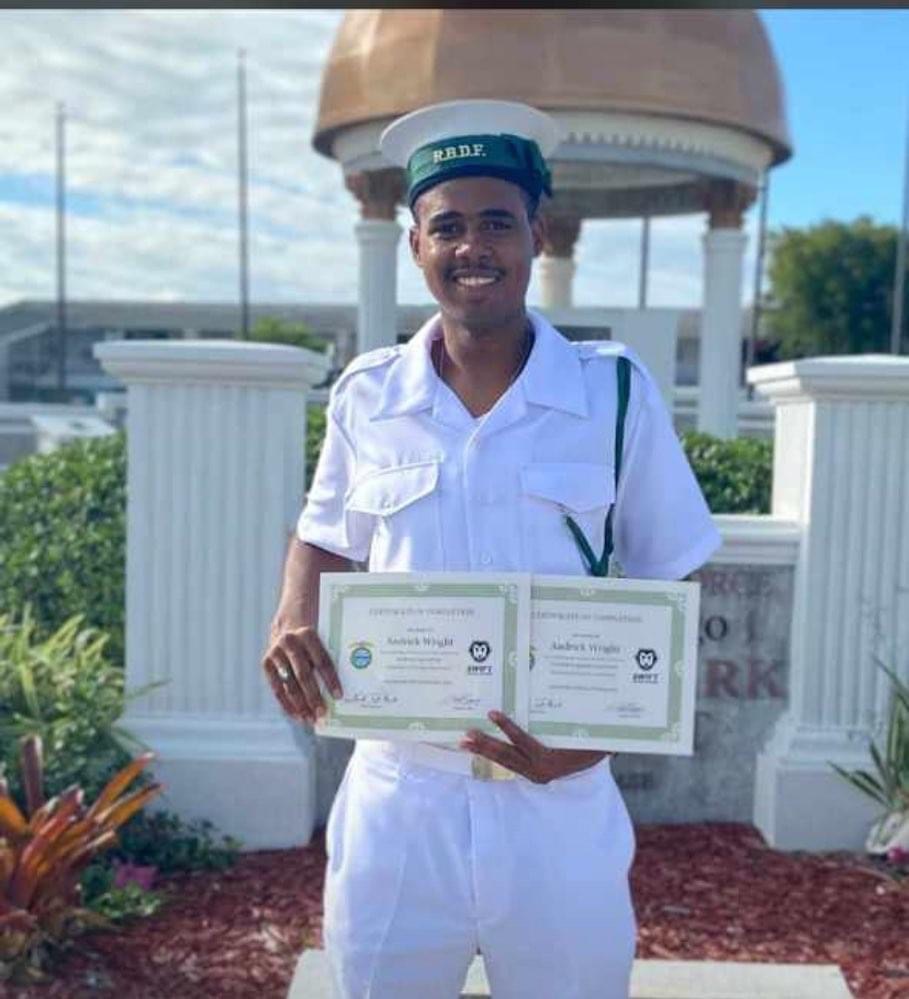 Andrick Wright in white uniform holding certificates