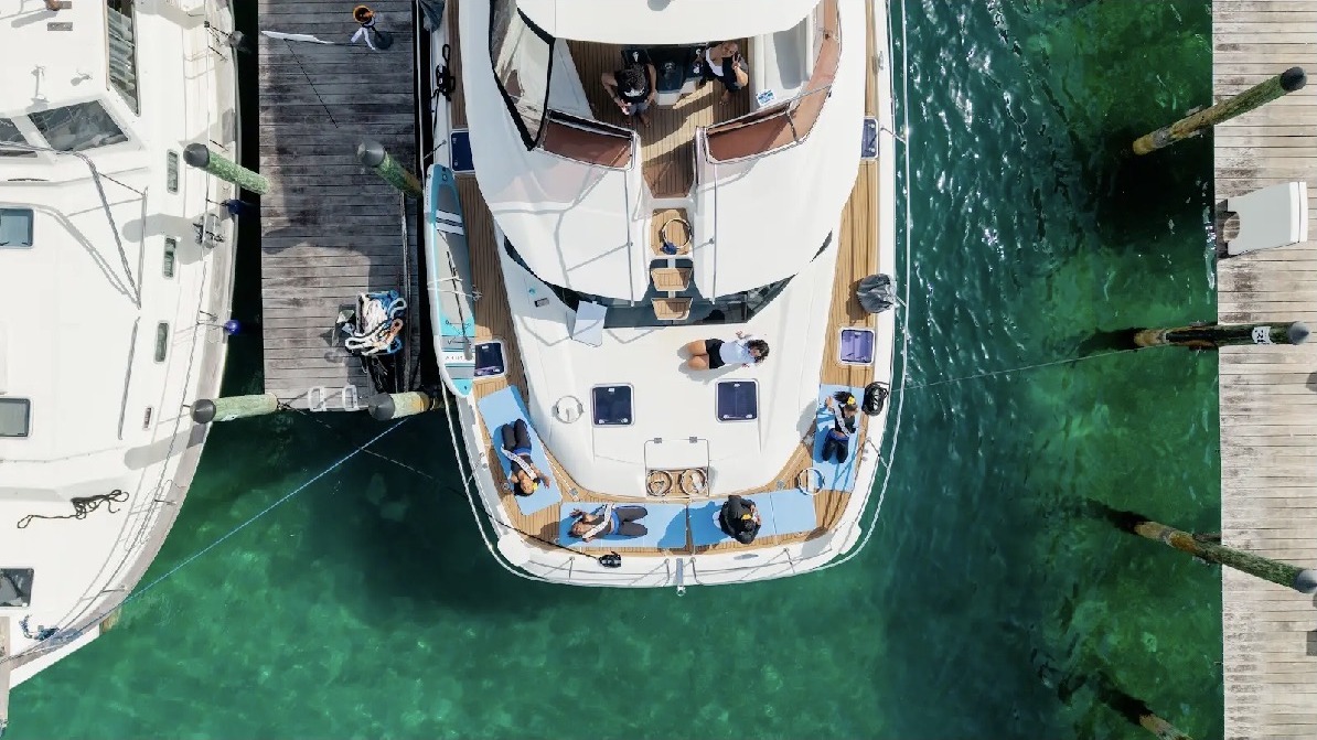 Aerial view of a Pilates group on a docked yacht over turquoise water