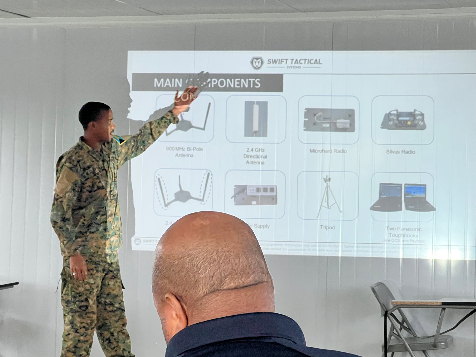 Instructor briefing a group on unmanned aircraft system components using a projected diagram