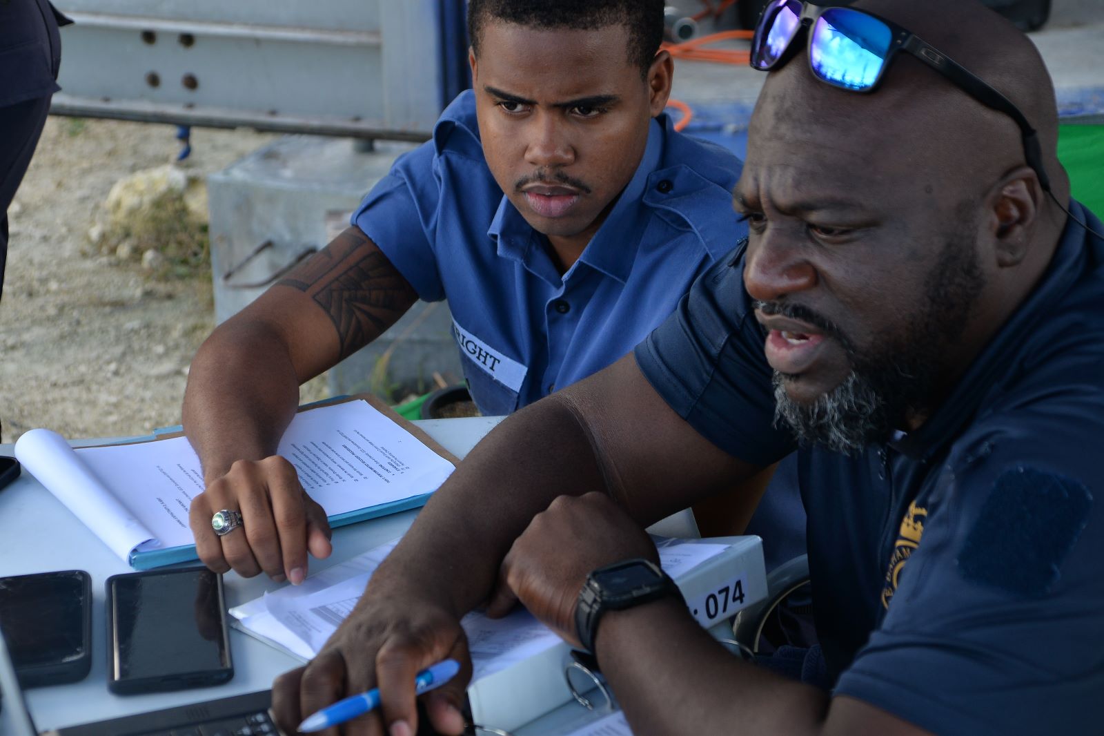A FlyWright instructor reviewing mission documents with a trainee at an outdoor table
