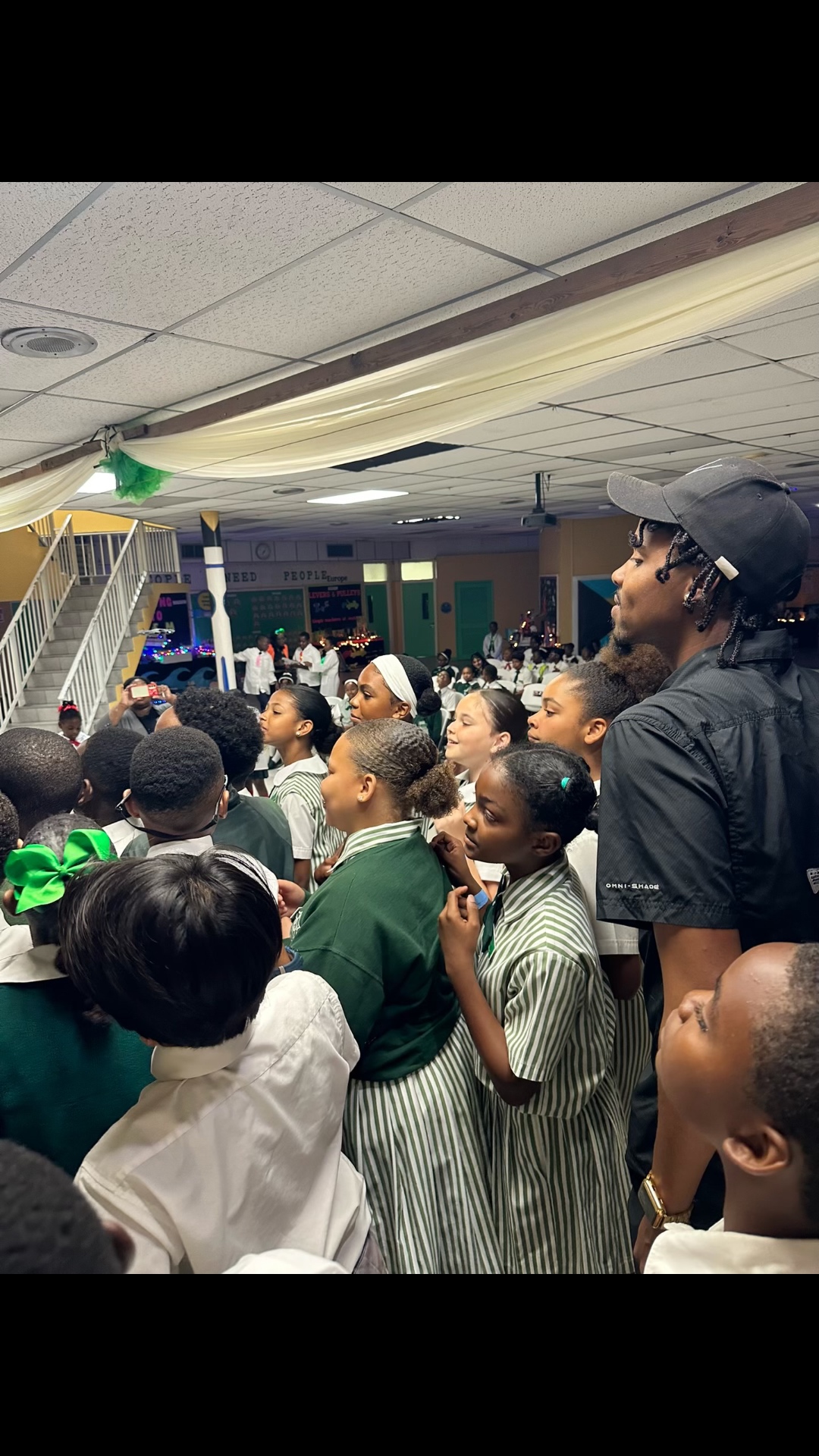 Schoolgirls watching a small drone demonstration during a school assembly