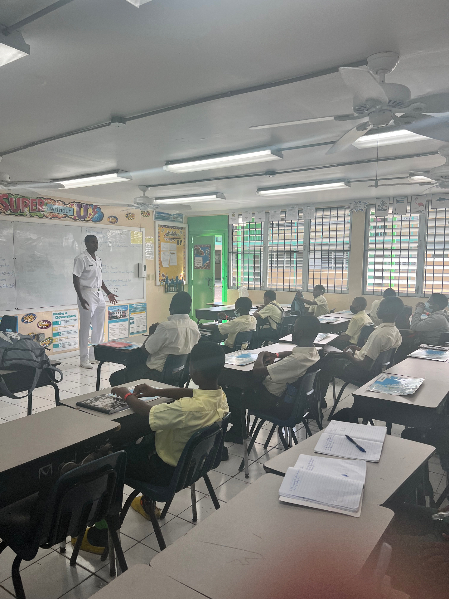 FlyWright instructor in white uniform speaking to a classroom of students during a school visit