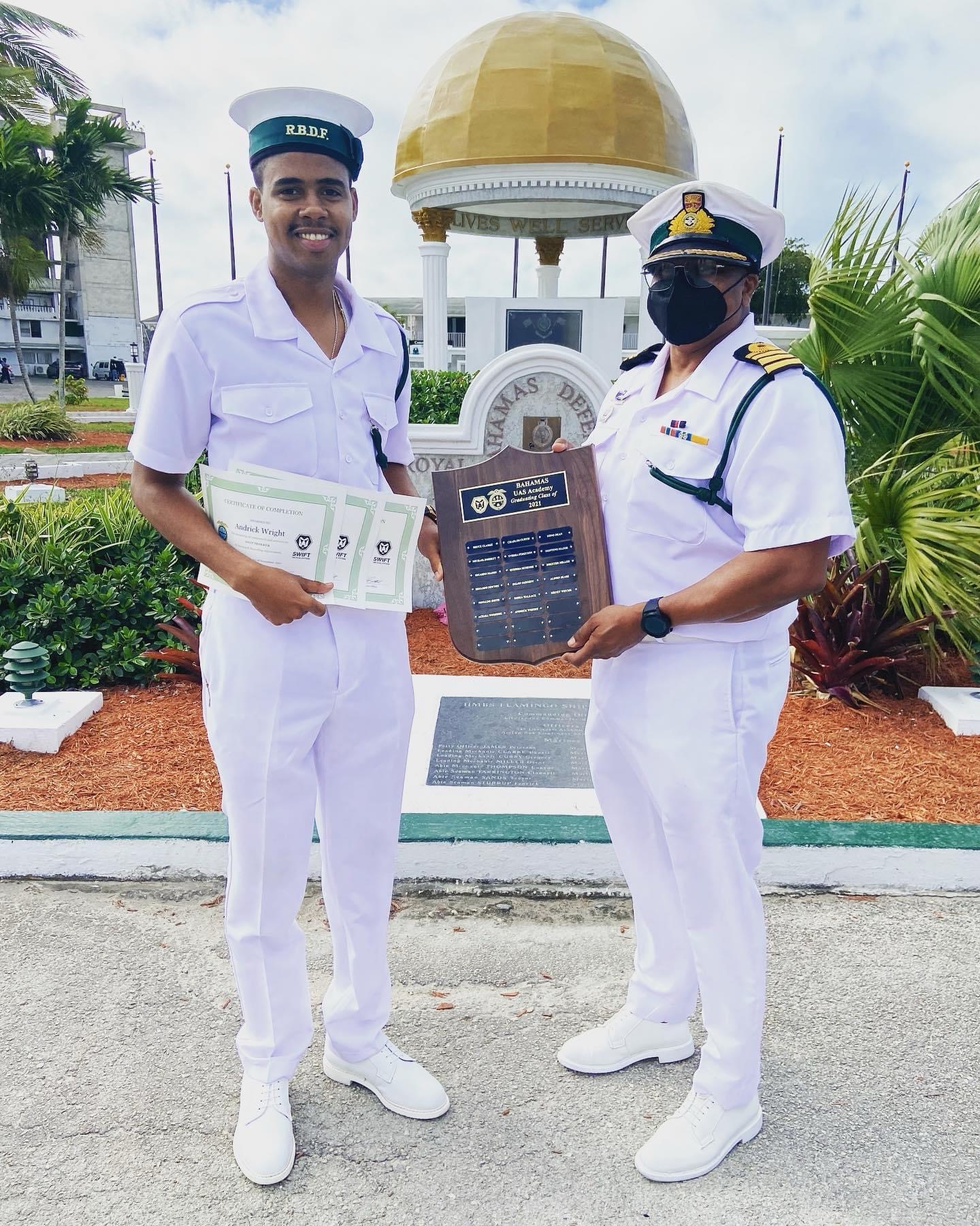 Andrick Wright and another uniformed person holding certificates and a plaque